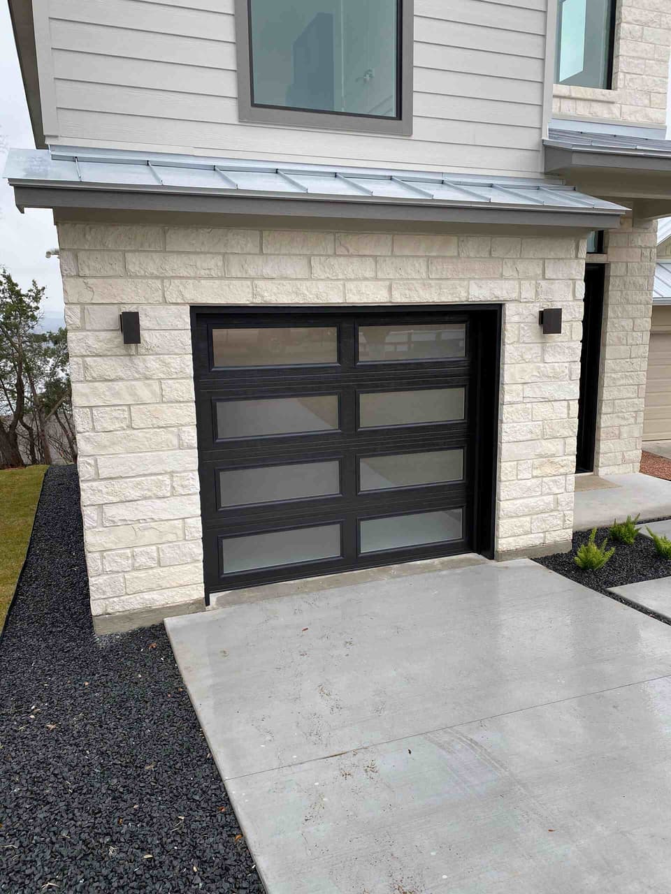 Modern glass-panel garage door installed by Door Pro Plus on a stone home in the Texas Hill Country