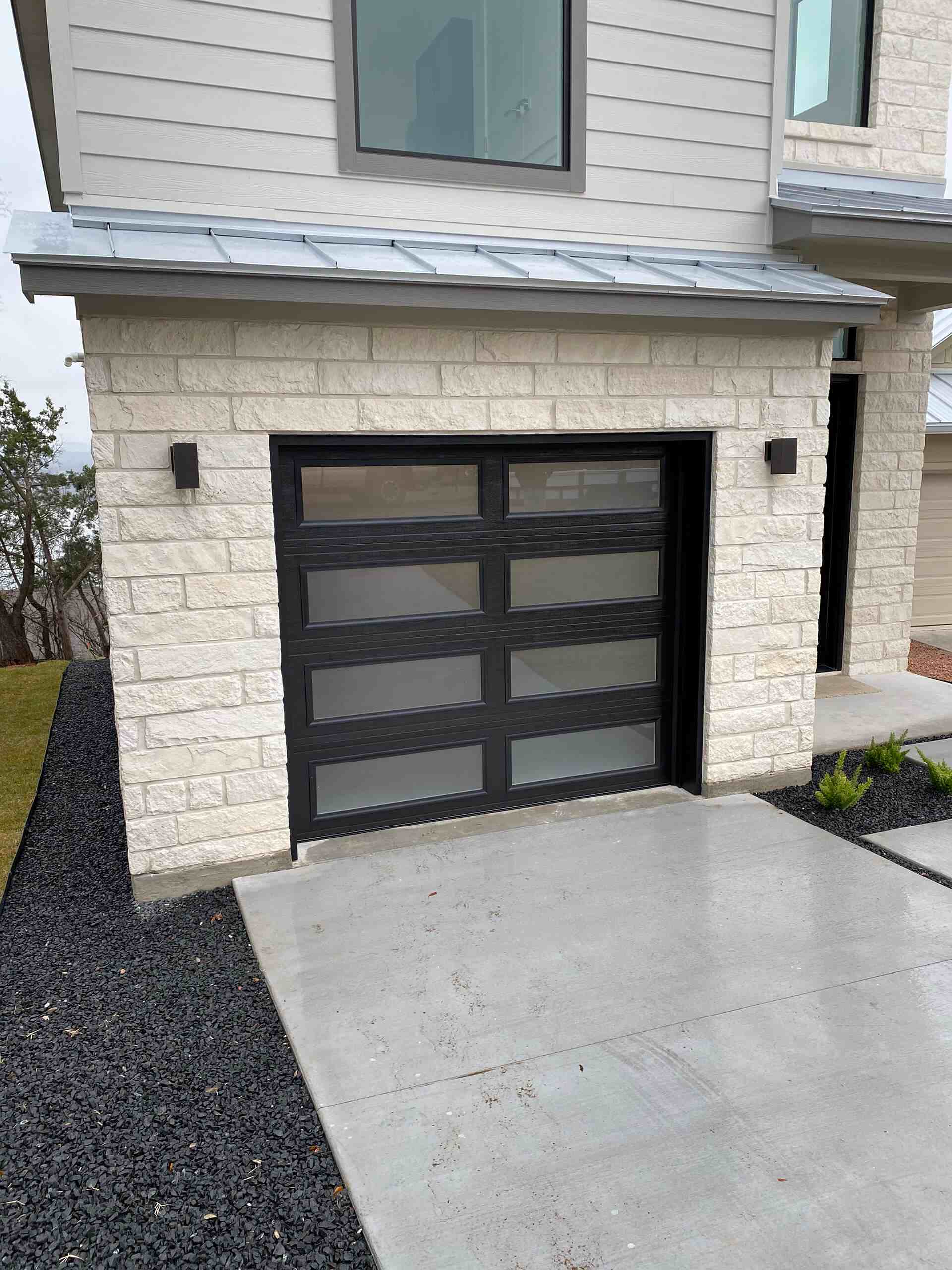 Modern glass-panel garage door installed by Door Pro Plus on a stone home in the Texas Hill Country