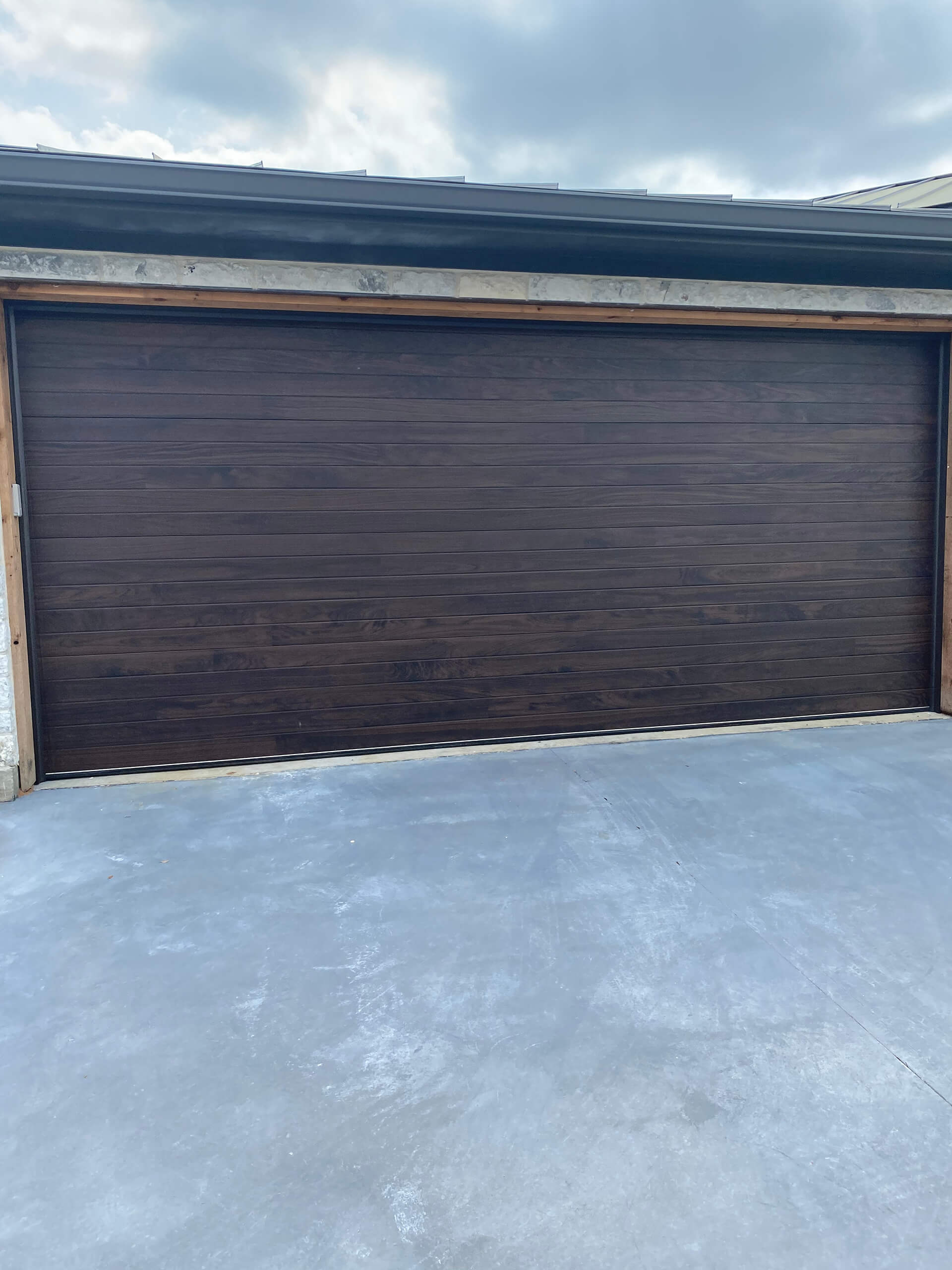 Dark wood-tone garage door installed by Door Pro Plus on a home in Marble Falls, TX