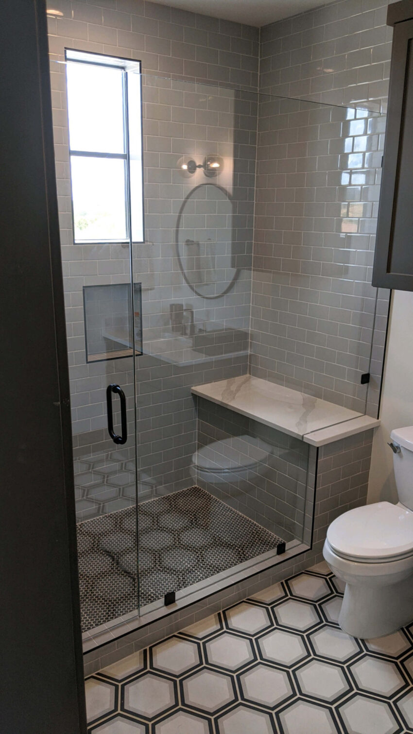 Frameless glass shower door with matte black hardware and hexagon floor tile, installed by Door Pro Plus in a Texas Hill Country bathroom